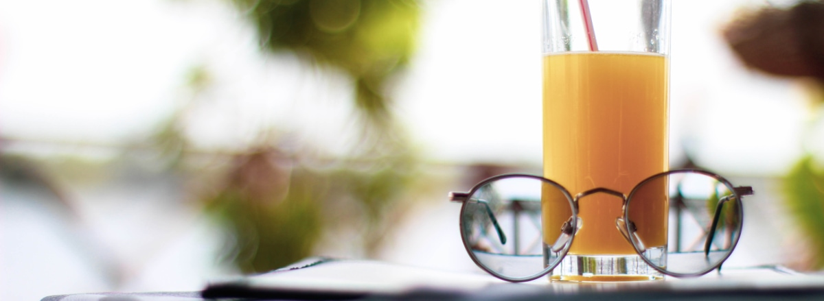 Eyeglasses and a refreshing orange juice resting on a table outdoors